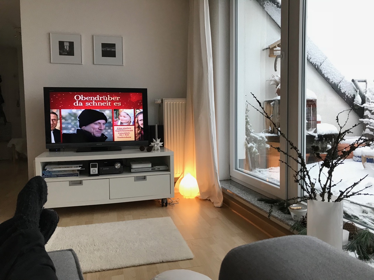 Blick auf den TV mit dem Film "Obendrüber das schneit es" und Blick auf die verschneite Terrasse