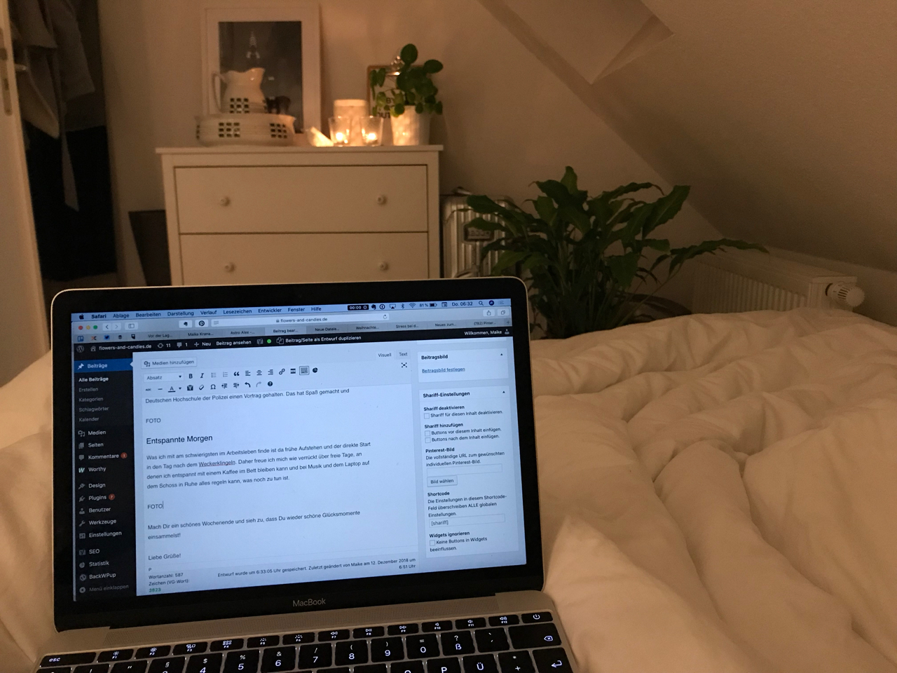 Kaffee im Bett: Laptop auf dem Schoss, im Hintergrund brennen Kerzen