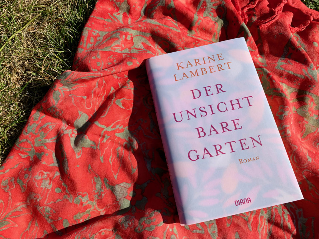 Buch "Der unsichtbare Garten" auf einem Tuch auf einer Wiese liegend