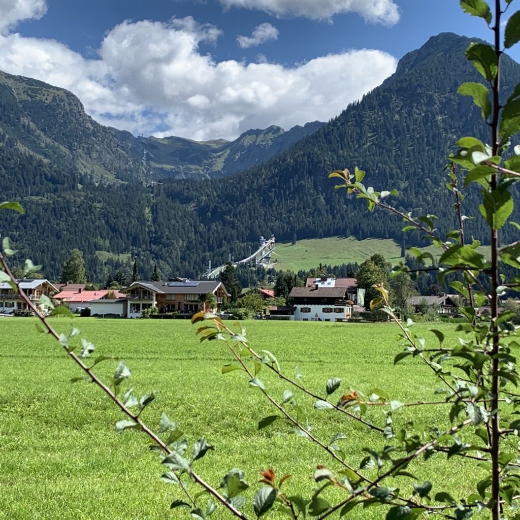 Oberstdorf: Blick über die große Wiese über Oberstdorf mit Skisprungschanze und Nebelhorn im Hintergrund