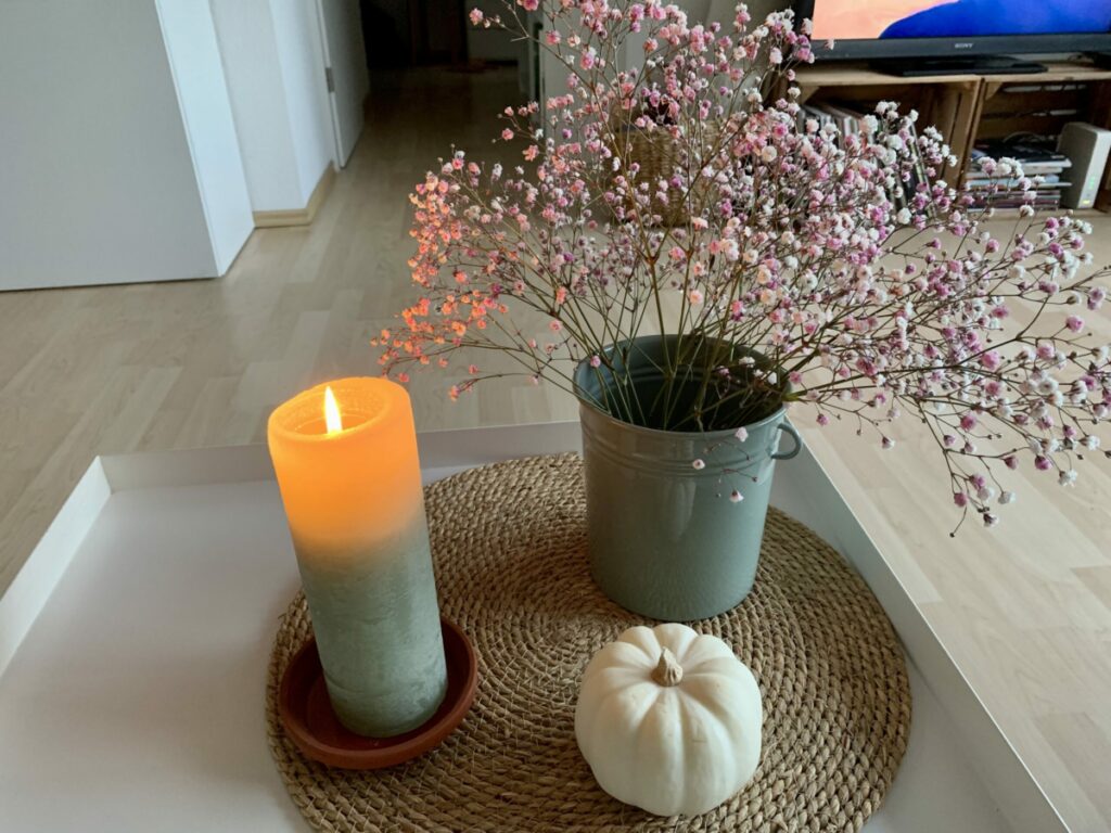 Herbststimmung: Cocuhtisch mit Vase und rosé Schleierkraut, Kerze und Kürbis