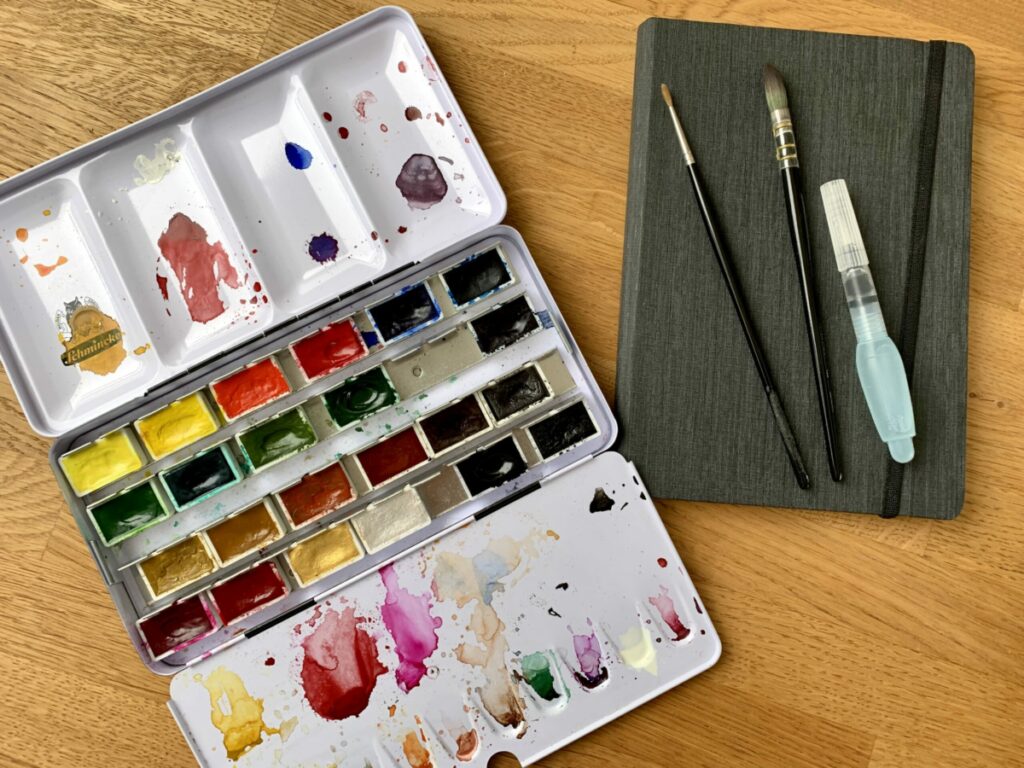 Aquarellkasten mit Pinseln und Büchern