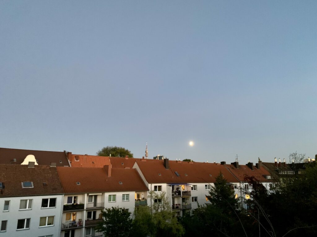 Zunehmender Mond (drei Tage vor Vollmond) über den Häuserdächern
