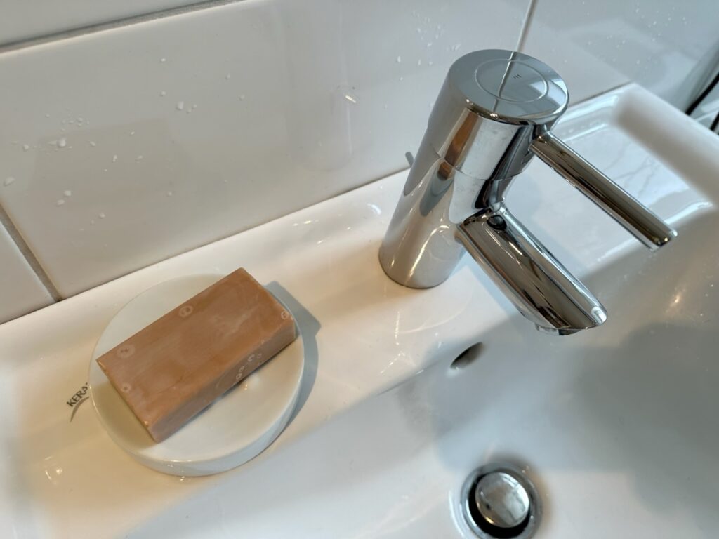 Waschbecken mit Seifenschale und orange-braun-farbener Seife in einer Seifenschale